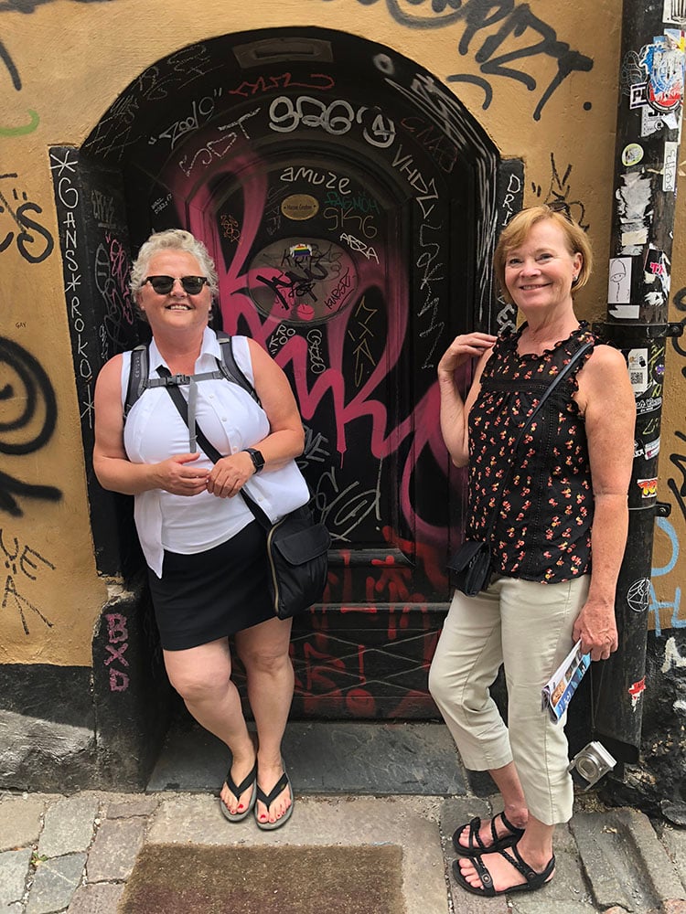 Two women by a graffiti-filled doorway