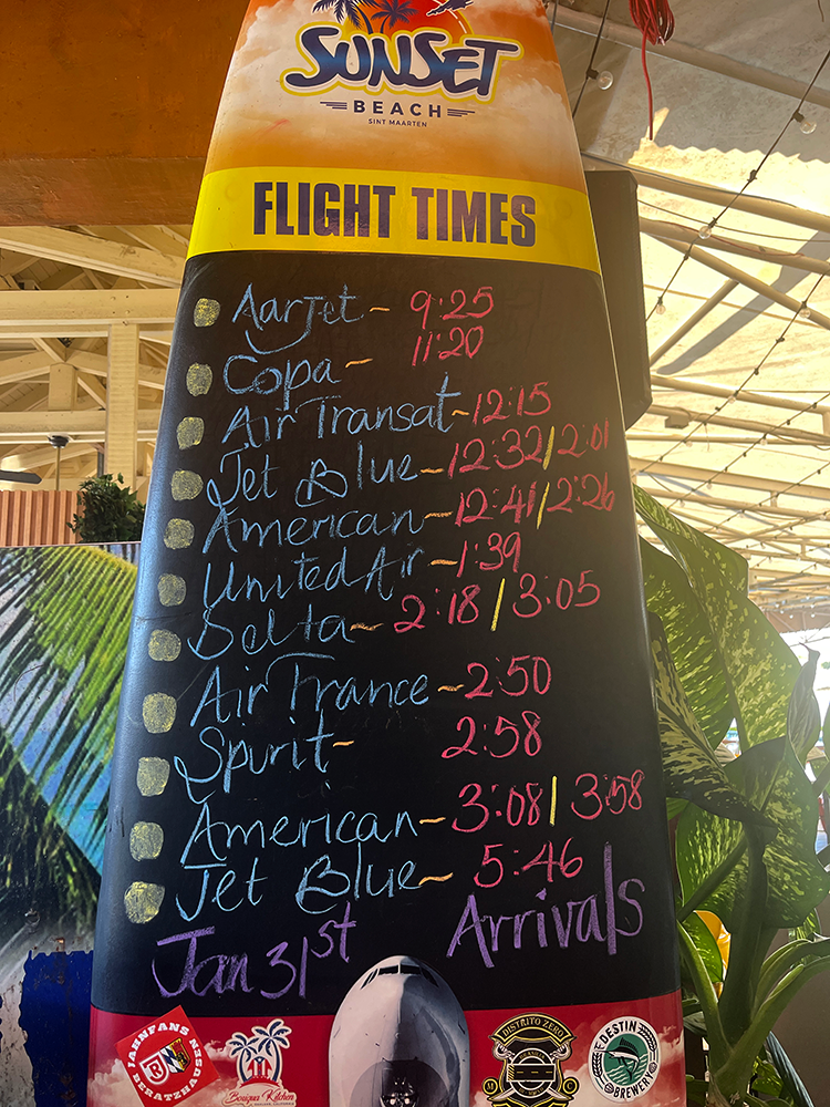 Chalkboard that looks like a Surfboard lists the times planes will be landing